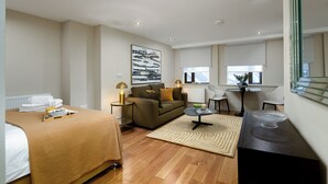 A hotel room with a bed, a sofa, a dining table, and a chair.