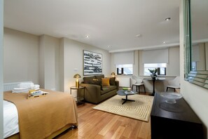 Una habitación de hotel con cama, sofá, mesa de comedor y una silla.