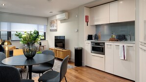 Una cucina moderna con mobili bianchi, forno integrato e zona pranzo con tavolo e sedie rotonde.