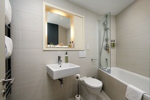 Un baño moderno con lavamanos, inodoro y bañera blancos.