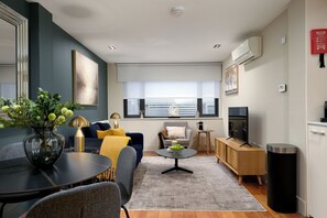 A modern living room with a sofa, coffee table, and a dining area with chairs and a table.