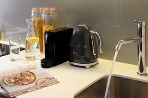 A kitchen counter with a kettle, a water bottle, a glass of water, and a cookbook.