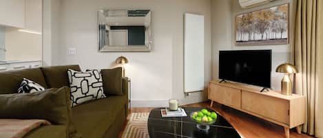 A living room with a sofa, coffee table, TV, and a radiator.