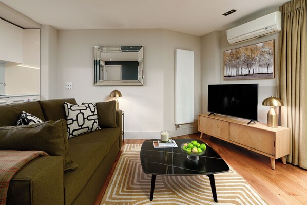 A living room with a sofa, coffee table, TV, and a radiator.