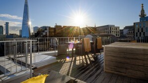 A rooftop terrace with a view of the city skyline, including a prominent skyscraper.