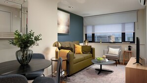 A modern living room with a sofa, coffee table, and a dining area.