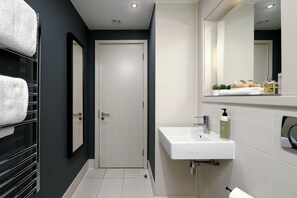 Une salle de bain moderne avec un lavabo blanc, un miroir et un porte-serviettes.