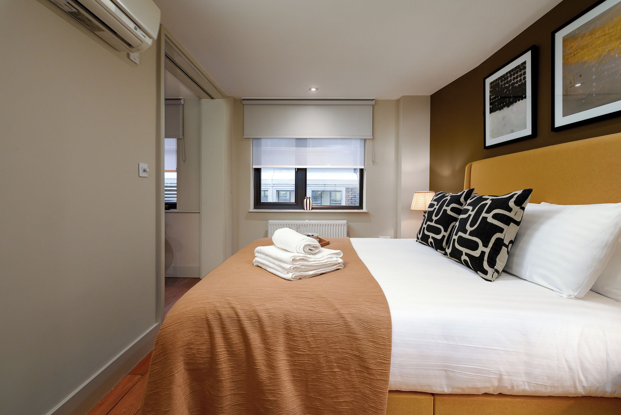 Habitación de hotel con cama, ventana, radiador y perchero para toallas.