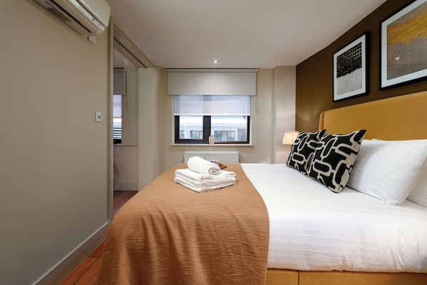 Une chambre d’hôtel avec un lit, une fenêtre, un radiateur et un porte-serviettes.