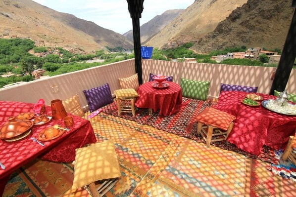 A terrace with tables set for dining, featuring a mountainous backdrop.