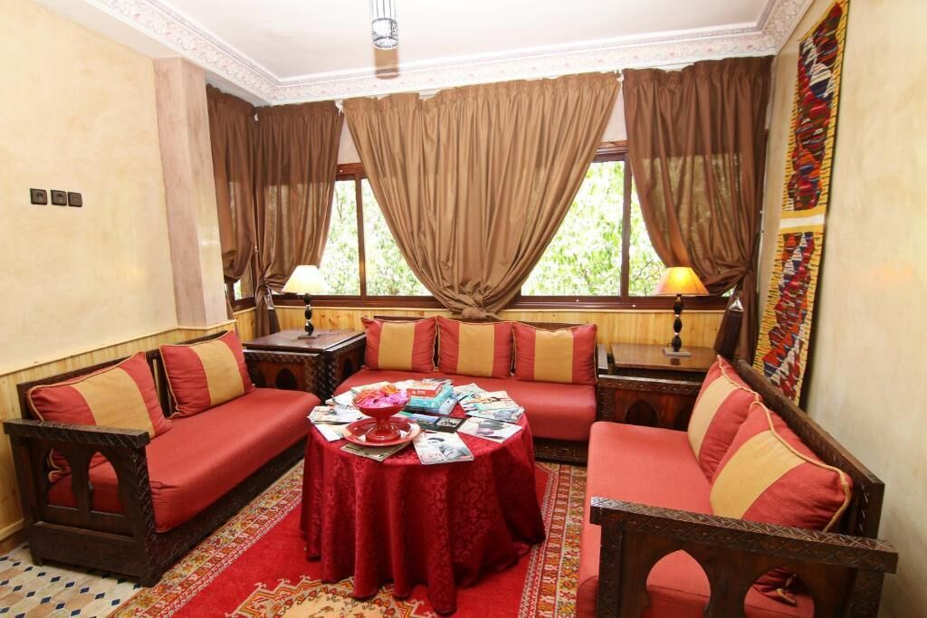 A cozy room with a red sofa set, a round table with magazines, and two lamps.
