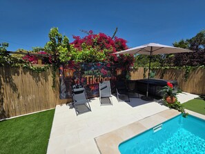 Un jardin avec une piscine, un espace salon extérieur, une fresque murale et une clôture en bois.