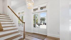 Eine Treppe mit Holzboden und Holzhandlauf führt zu einer weißen Tür mit Glasfeldern.