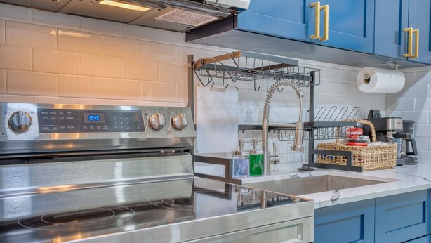 A modern kitchen with stainless steel appliances, a built-in oven, and blue cabinets.
