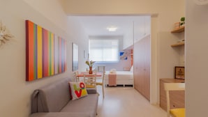 Un espacio habitable moderno y funcional, con sofá, mesa de comedor y zona de kitchenette.
