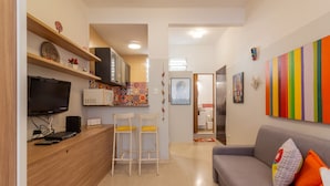 Una cocina moderna con televisor de pantalla plana, estanterías de madera y un salpicadero colorido.