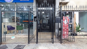 Un establecimiento para lavado de mascotas con una puerta metálica, un letrero azul con información de contacto y una entrada visible.