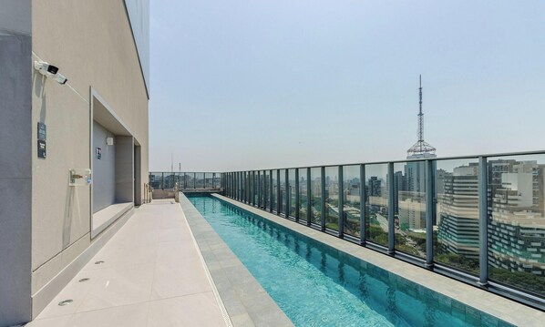 A rooftop swimming pool with a glass railing, a clear view of the cityscape, and a modern building facade. - Building w/ Pool and Gym in Paraiso - ONP (São Paulo)