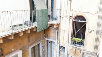Un patio de varios niveles con balcones, una escalera y macetas.