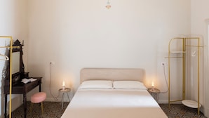 Una habitación de hotel con una cama grande, una araña, un espejo, un tocador y un vestidor.