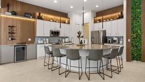 Una cocina moderna con una isla central, taburetes de bar y electrodomésticos integrados.