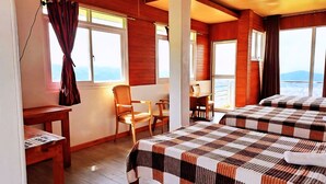 Habitación de hotel con dos camas, un escritorio de madera, una silla y vista a la ciudad.