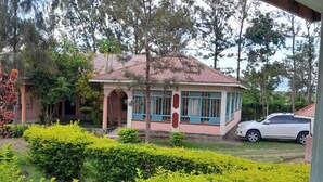 A house with a red roof, a porch, and a car parked in the driveway.