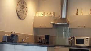 A modern kitchen with a central island, built-in appliances, and a checkered floor. - Villa on the tip of the CAP FERRET peninsula (CAP FERRET)