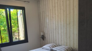 A single bed with striped bedding in a room with wooden panel walls and a window with a view of greenery. - Villa on the tip of the CAP FERRET peninsula (CAP FERRET)