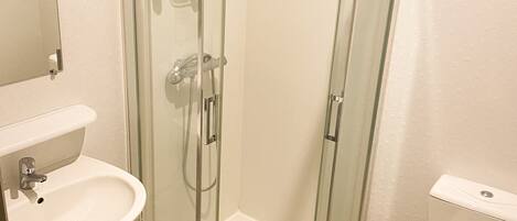 Un baño moderno con ducha de vidrio, lavamanos e inodoro.
