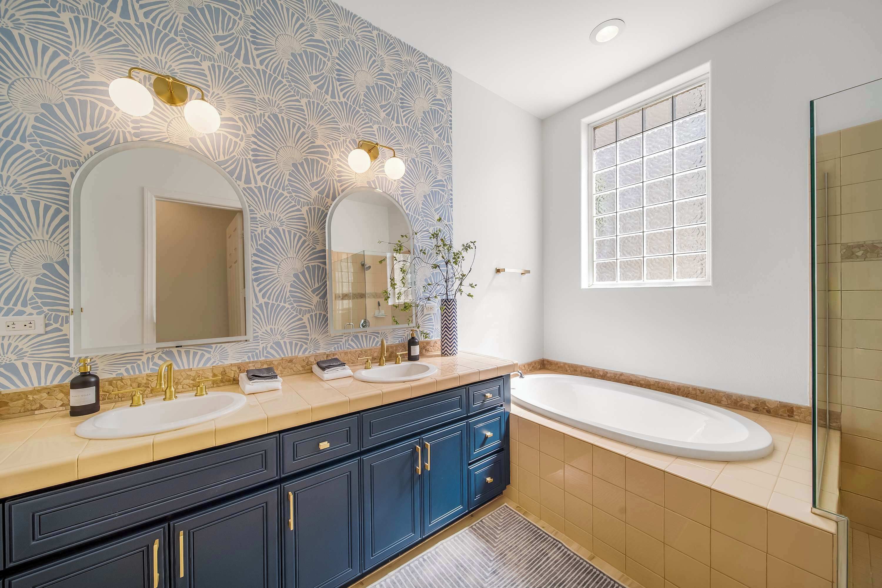 A bathroom with two sinks, a large mirror, and a bathtub.