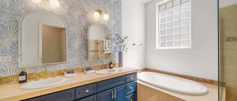 A bathroom with two sinks, a large mirror, and a bathtub.