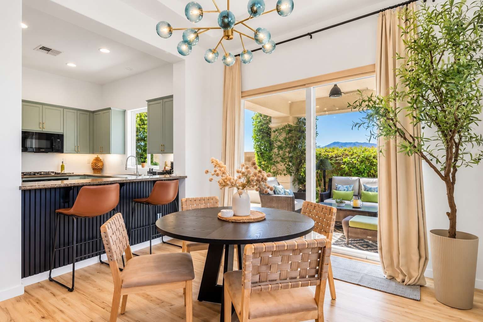 A modern kitchen with a dining area, a large window, and a view of the outdoors.