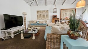 A living room with a flat-screen TV, a sofa, a coffee table, and a potted plant. - Toca do Fradinho - Pera 3 7Km da Praia (Silves)