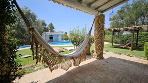 A hammock under a pergola, a swimming pool, and a small building in a garden. - Toca do Fradinho - Pera 3 7Km da Praia (Silves)