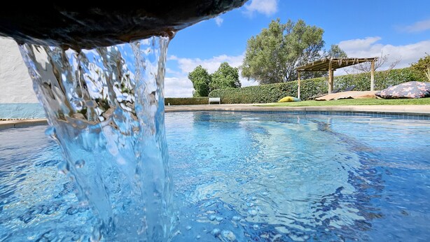 A swimming pool with clear water, a wooden pergola, and a bench in the background. - Toca do Fradinho - Pera 3 7Km da Praia (Silves)