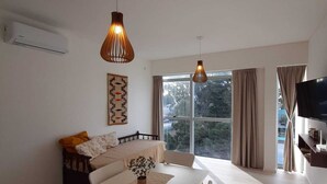 A modern living room with a dining table, chairs, a sofa, and a TV.