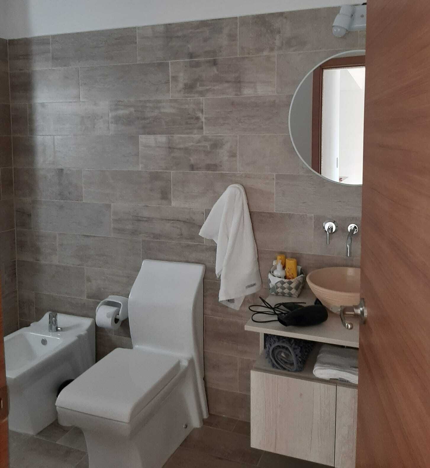 A bathroom with a toilet, sink, and mirror.