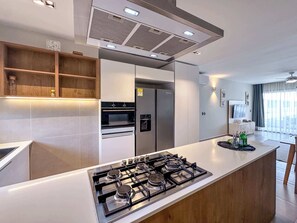 A modern kitchen with a central island, built-in oven, and refrigerator.