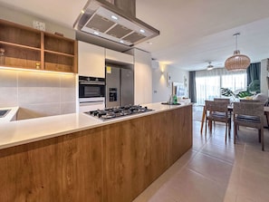A modern kitchen with a central island, built-in oven, and stainless steel appliances.