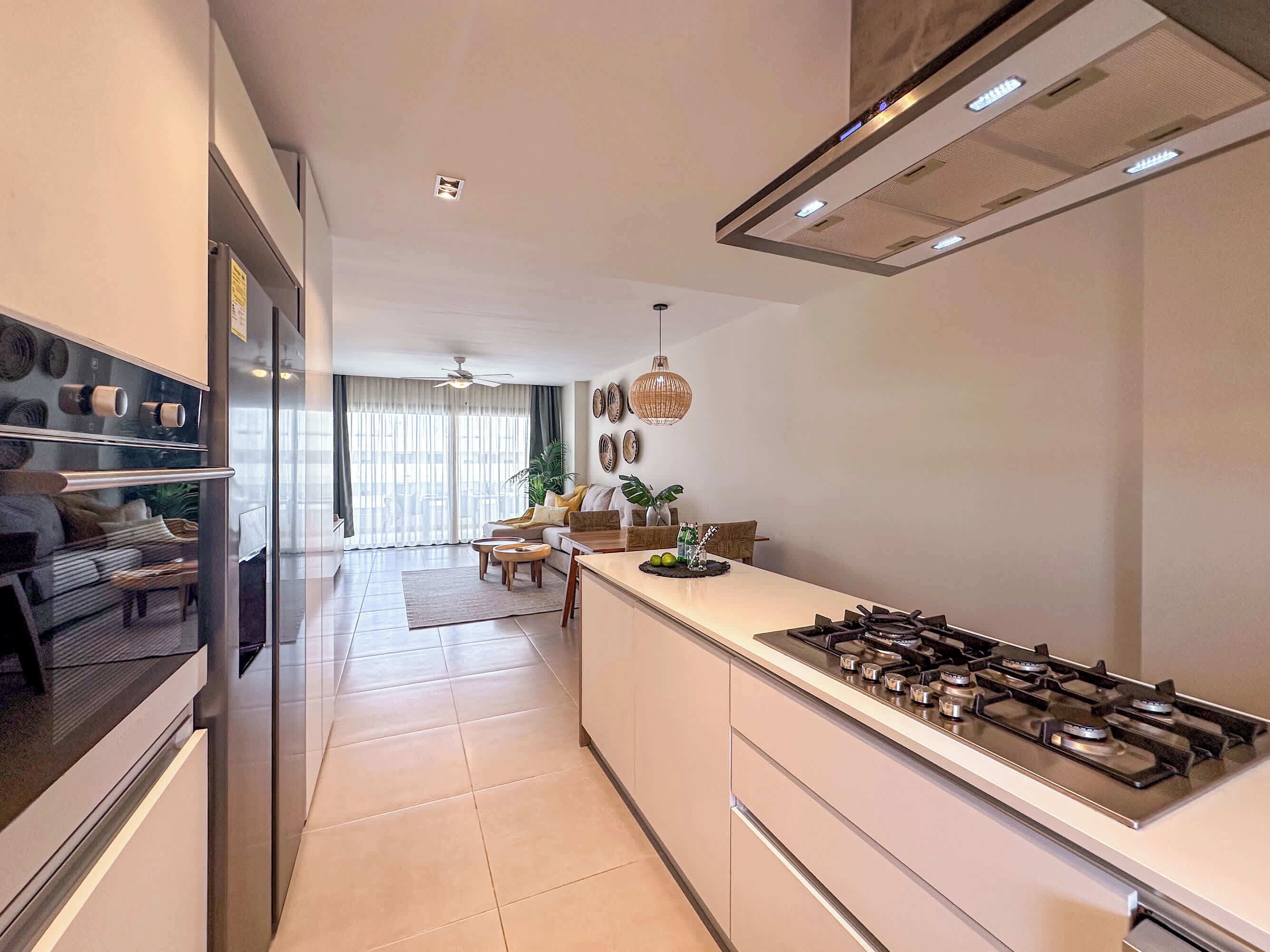 Una cucina moderna con isola centrale, elettrodomestici in acciaio inossidabile e zona pranzo con divano e tavolo.
