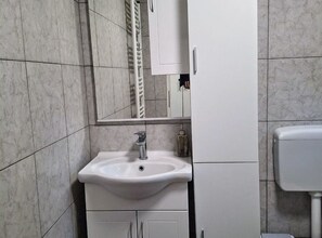 A bathroom with a white sink, a mirror, and a toilet.