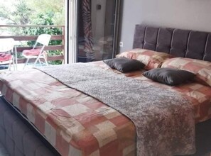 A bedroom with a bed, a window, and a chair outside.