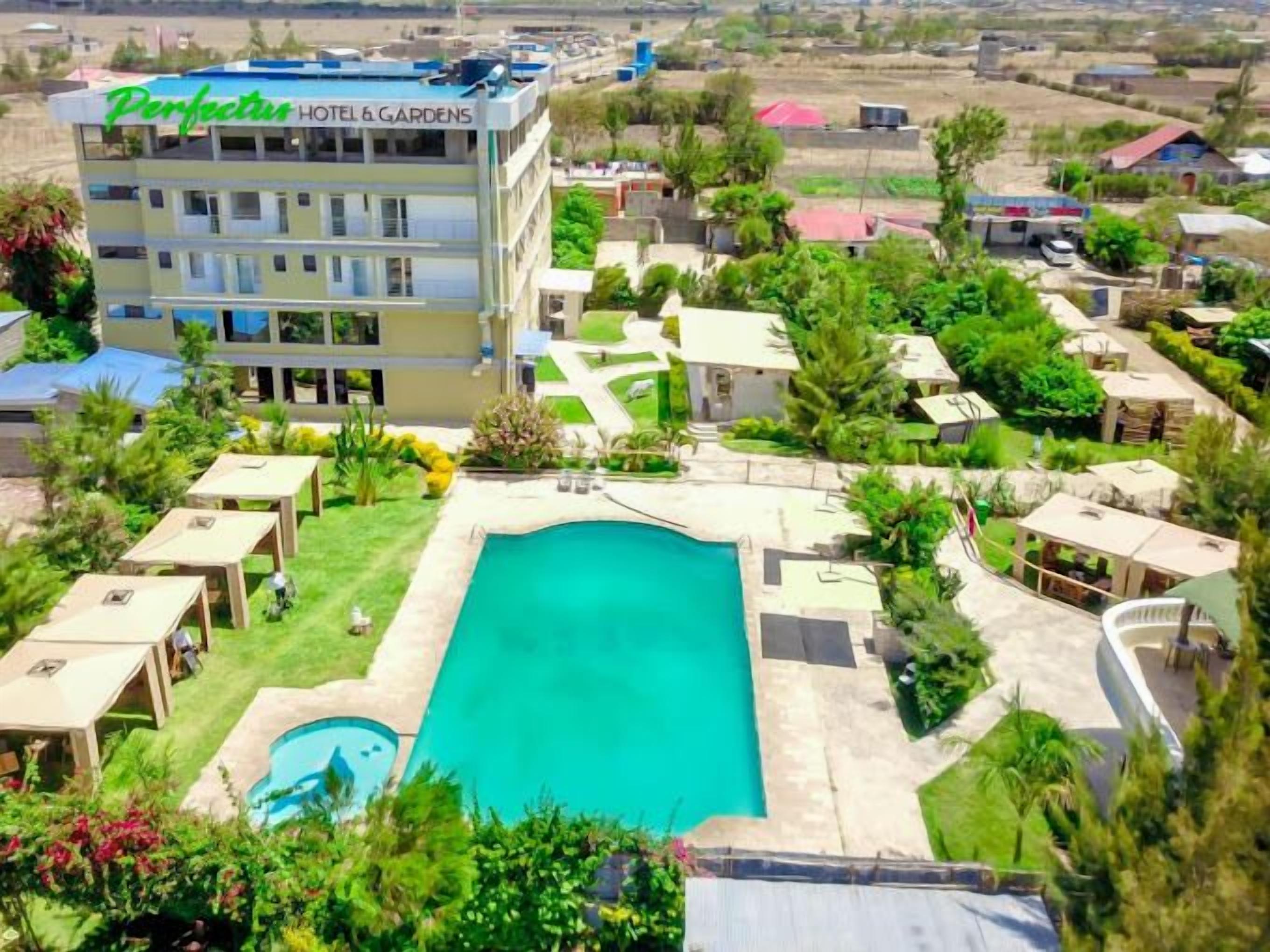 Un hotel con piscina rodeado de vegetación y varias habitaciones.