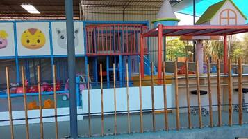 A children's play area with a fenced enclosure, a small building with a red roof, and a slide.
