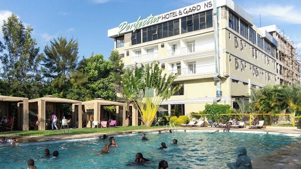 Een hotel met een zwembad, omringd door terrasjes en palmbomen.