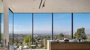 A modern kitchen with a large island, large windows, and a view of a cityscape. - Royal Oak - Exquisite Estate with Infinity Pool & Breathtaking Views (Encino)