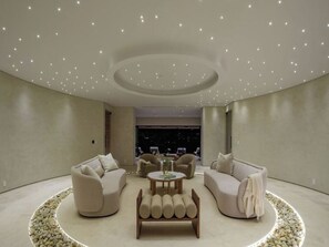 A modern, circular living room with a central coffee table, sofas, and a circular seating area with pebbles. - Royal Oak - Exquisite Estate with Infinity Pool & Breathtaking Views (Encino)