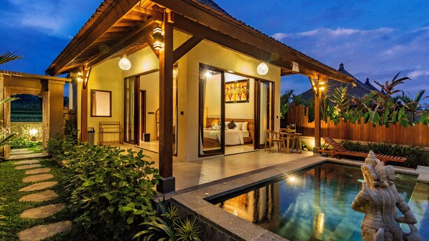 Una villa luminosa con piscina, un porche cubierto y un jardín.