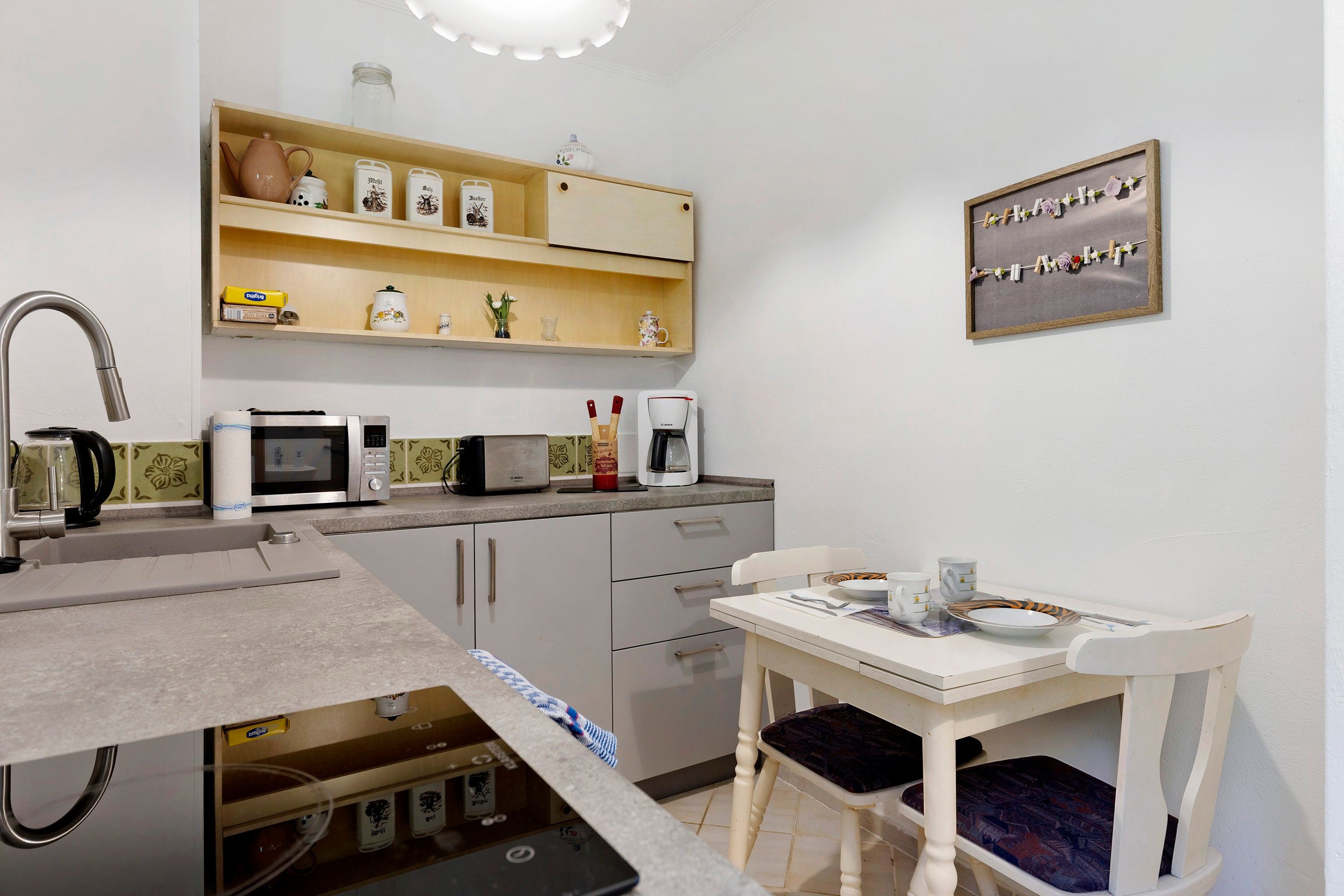 Une cuisine compacte équipée d’un évier, d’un four à micro-ondes, d’un grille-pain et d’une petite table à manger avec des chaises.